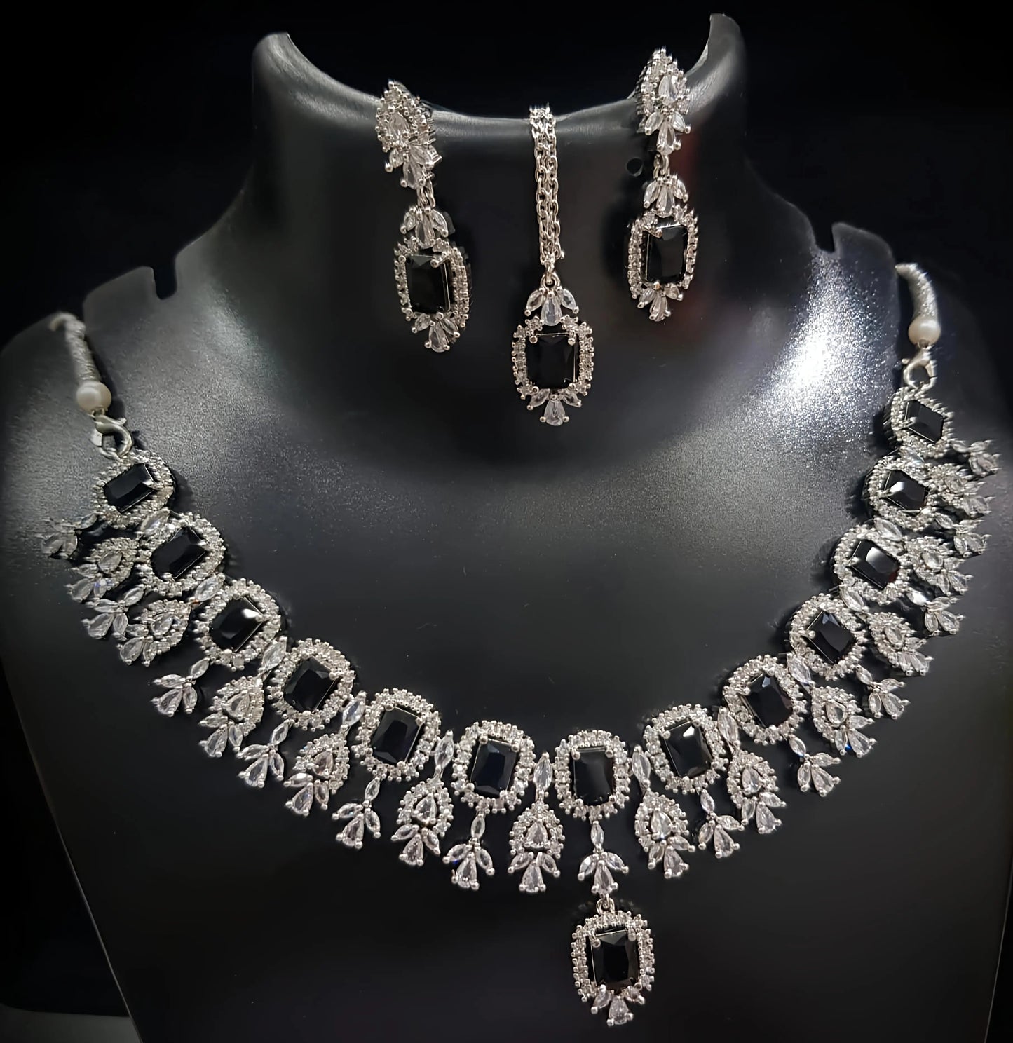 Necklace and earrings set on a black mannequin with a dark background