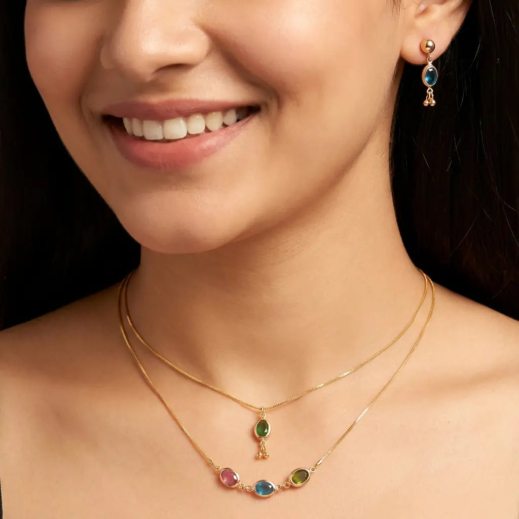 Close-up of a woman wearing a gold necklace with colorful gemstones and matching earrings.