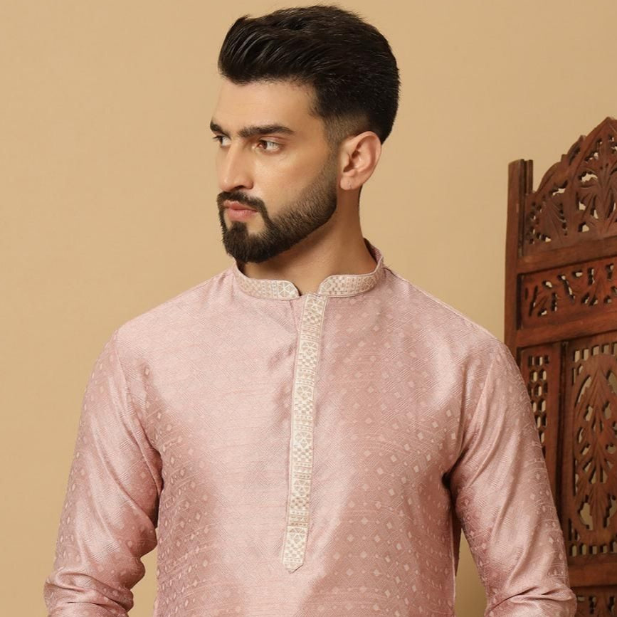 Man wearing a pink kurta with white embroidery against a beige background