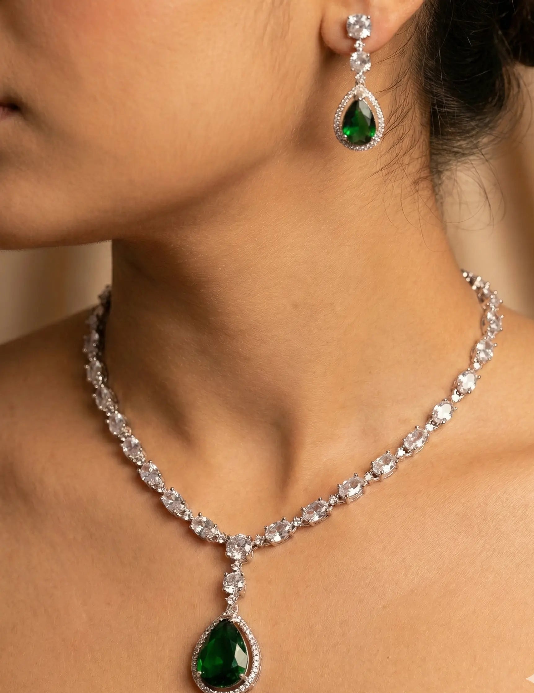 Necklace and earrings with green gemstones worn by a person