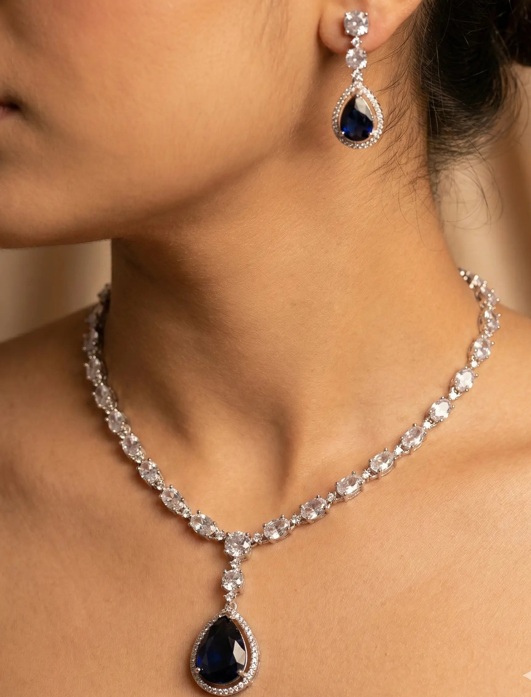 Jewelry set with necklace and earrings featuring blue gemstones on a neutral background