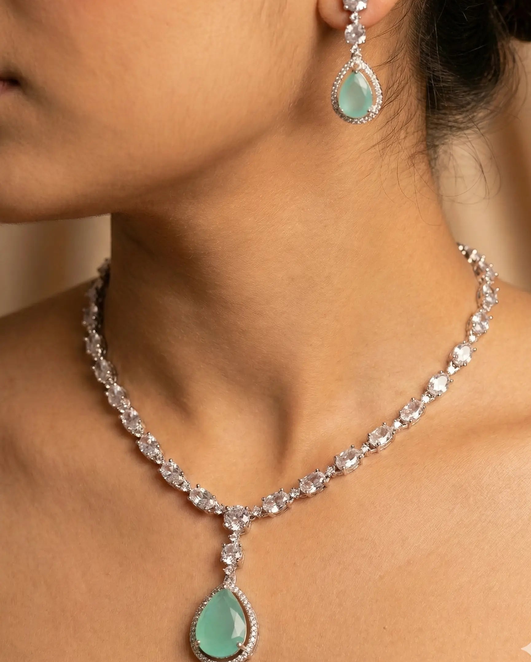 Turquoise necklace and earrings on a model against a neutral background