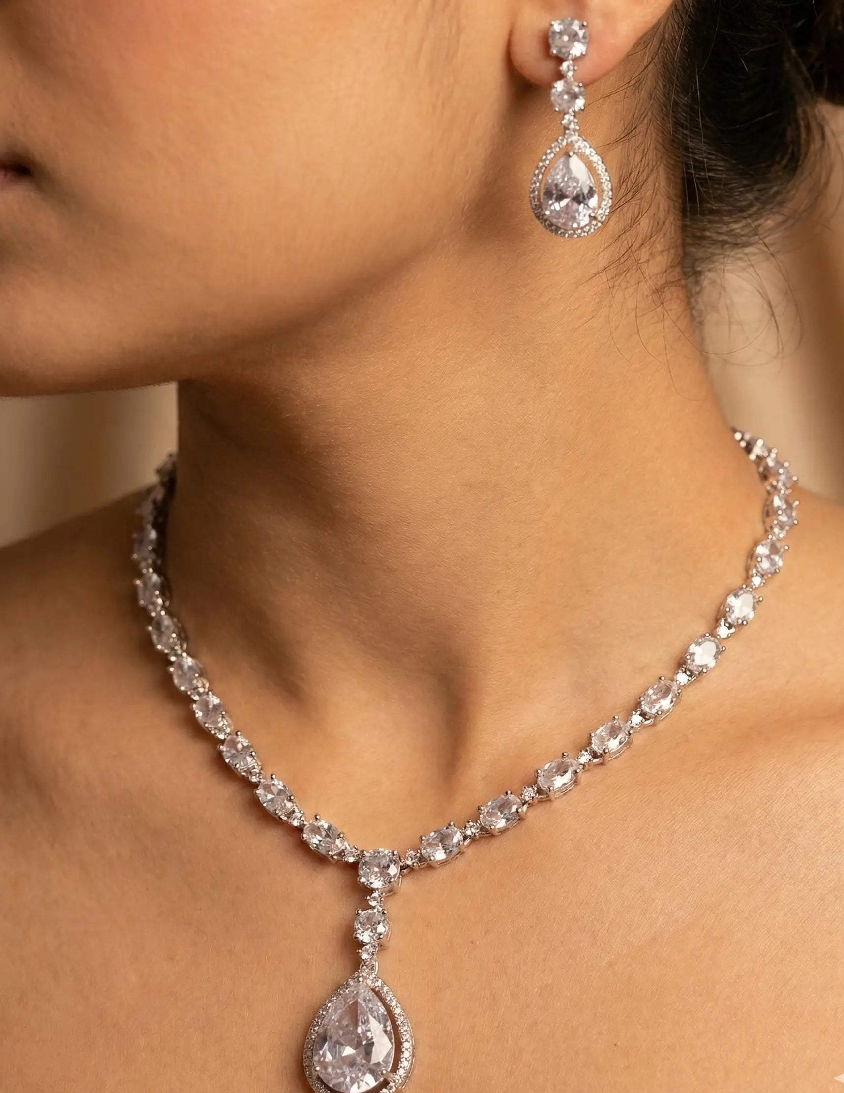 Diamond necklace and earrings on a model against a neutral background