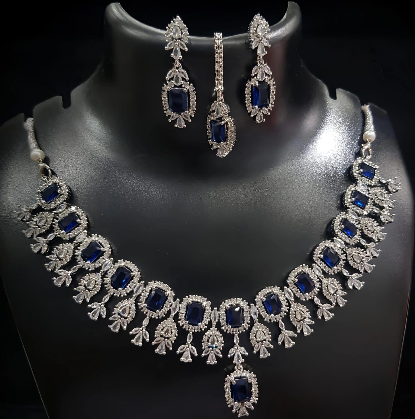 Jewelry set with necklace and earrings featuring blue stones on a black background