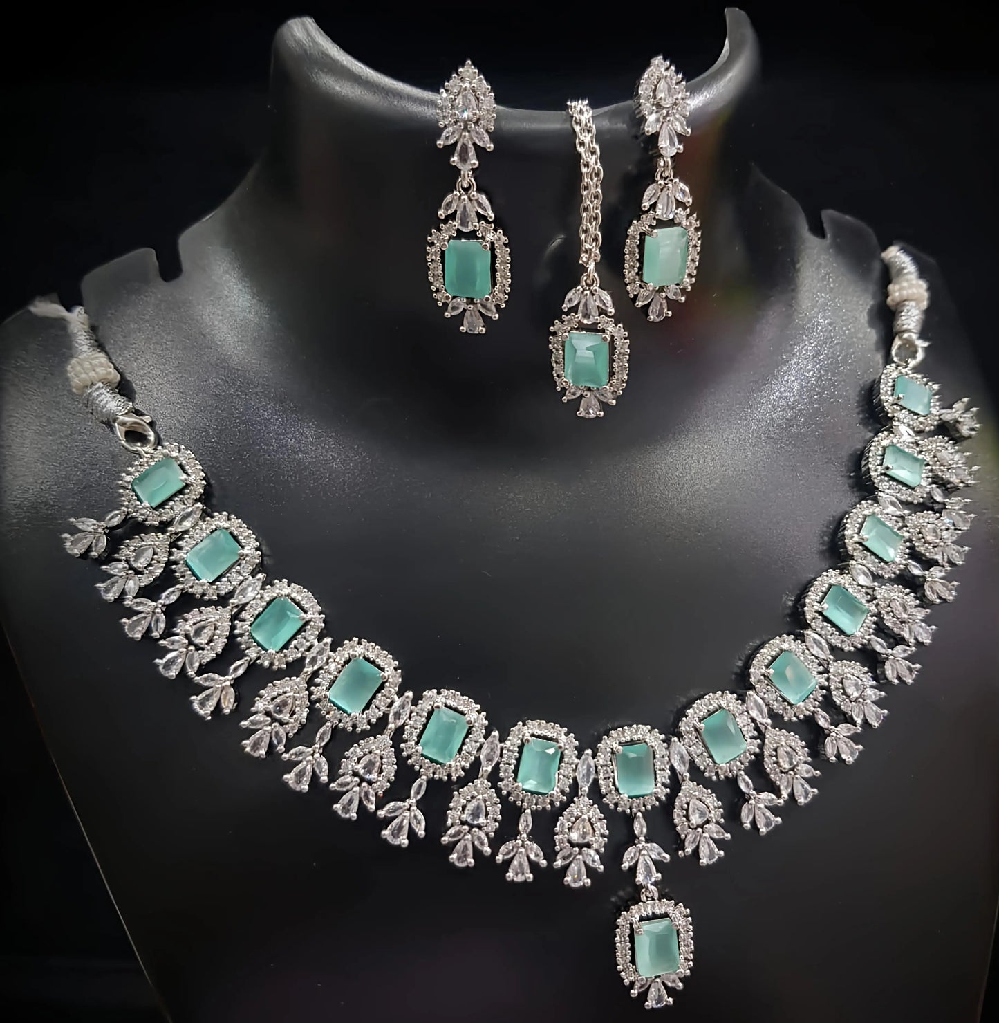 Necklace and earrings set with turquoise stones on a black mannequin
