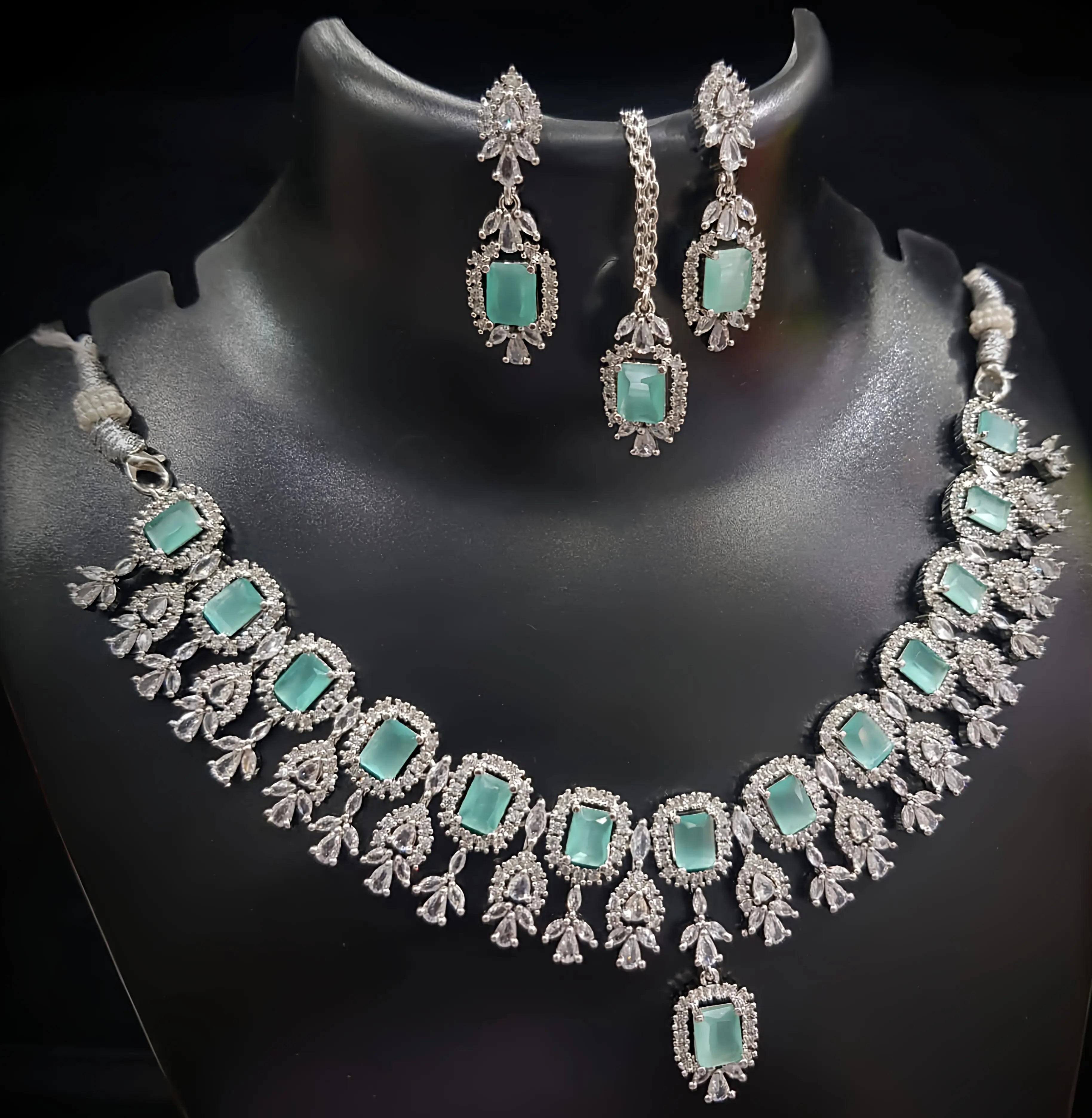 Necklace and earrings set with turquoise stones on a black mannequin