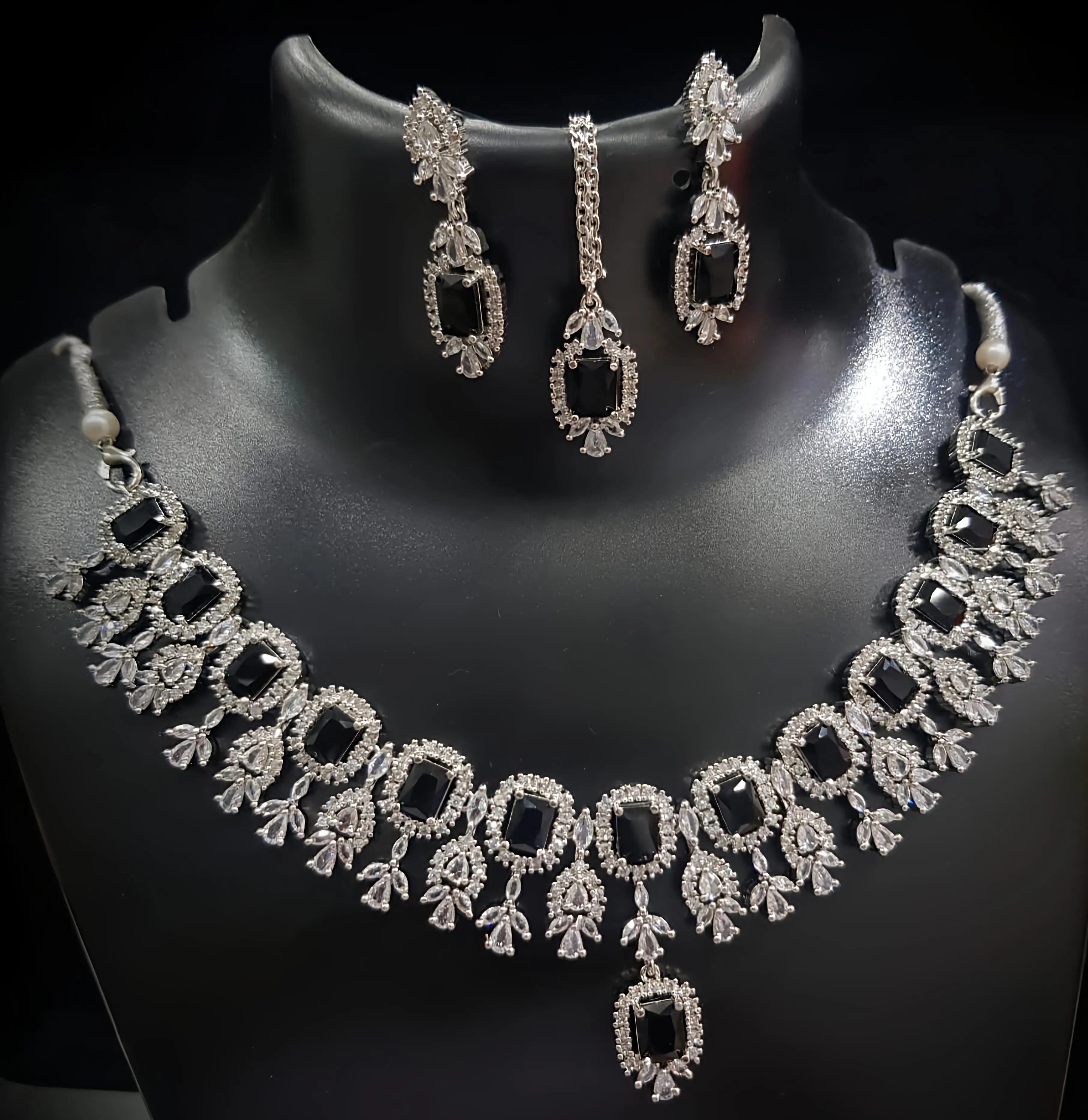 Necklace and earrings set on a black mannequin with a dark background