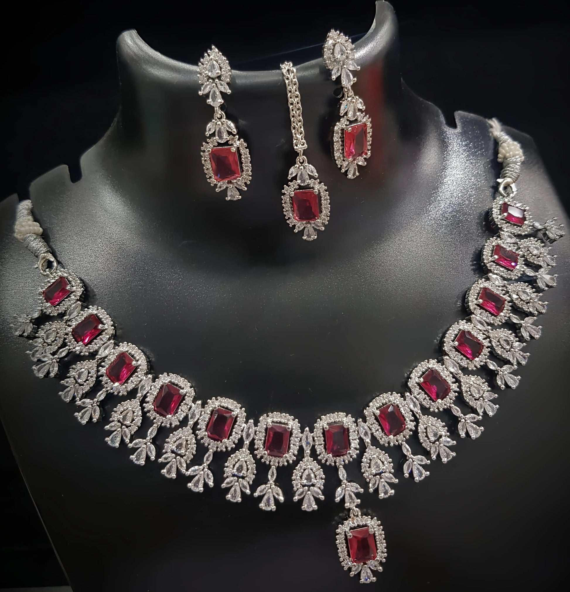 Jewelry set with necklace and earrings featuring red gemstones on a black background