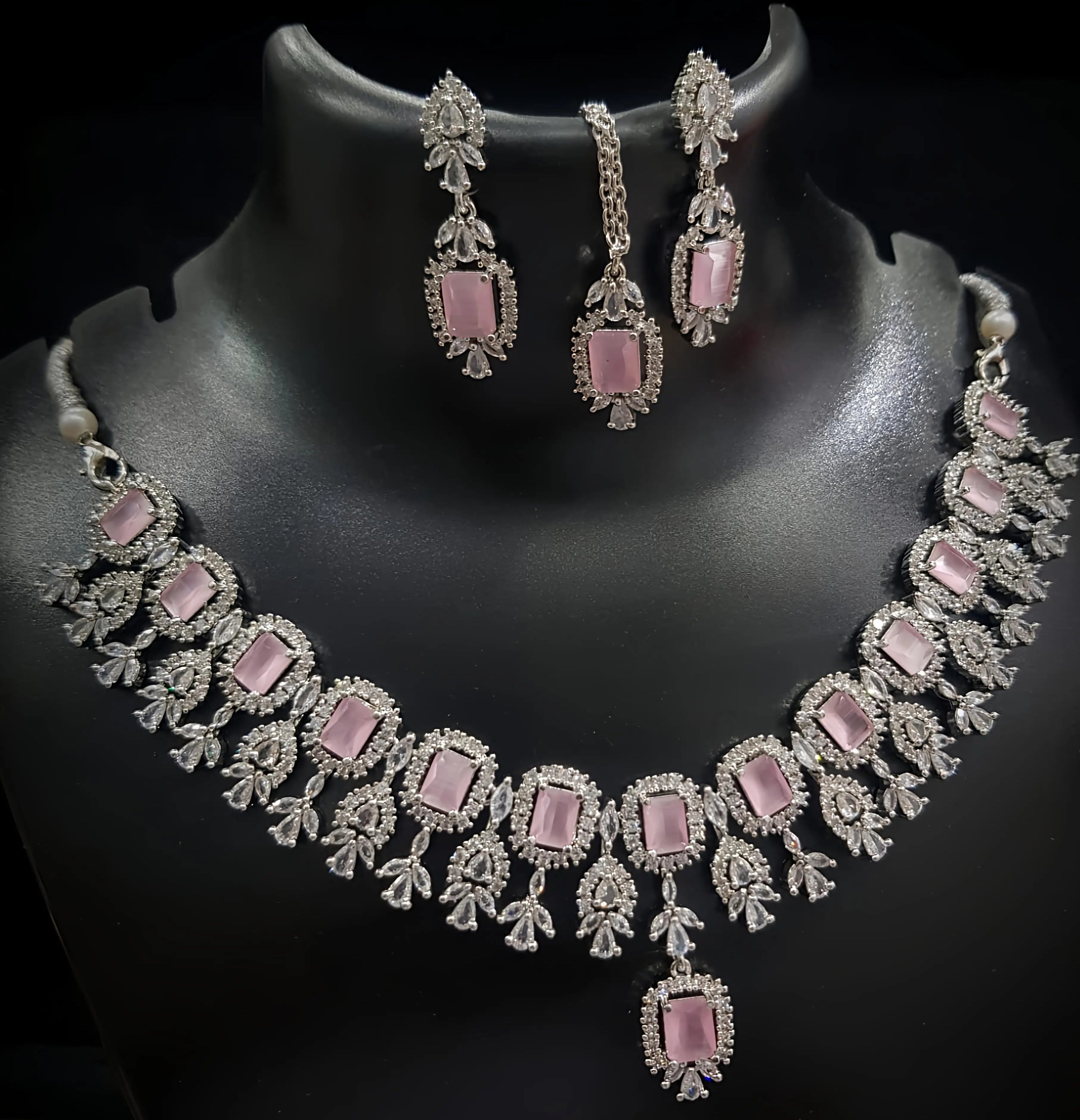 Necklace and earrings set with pink stones on a black background