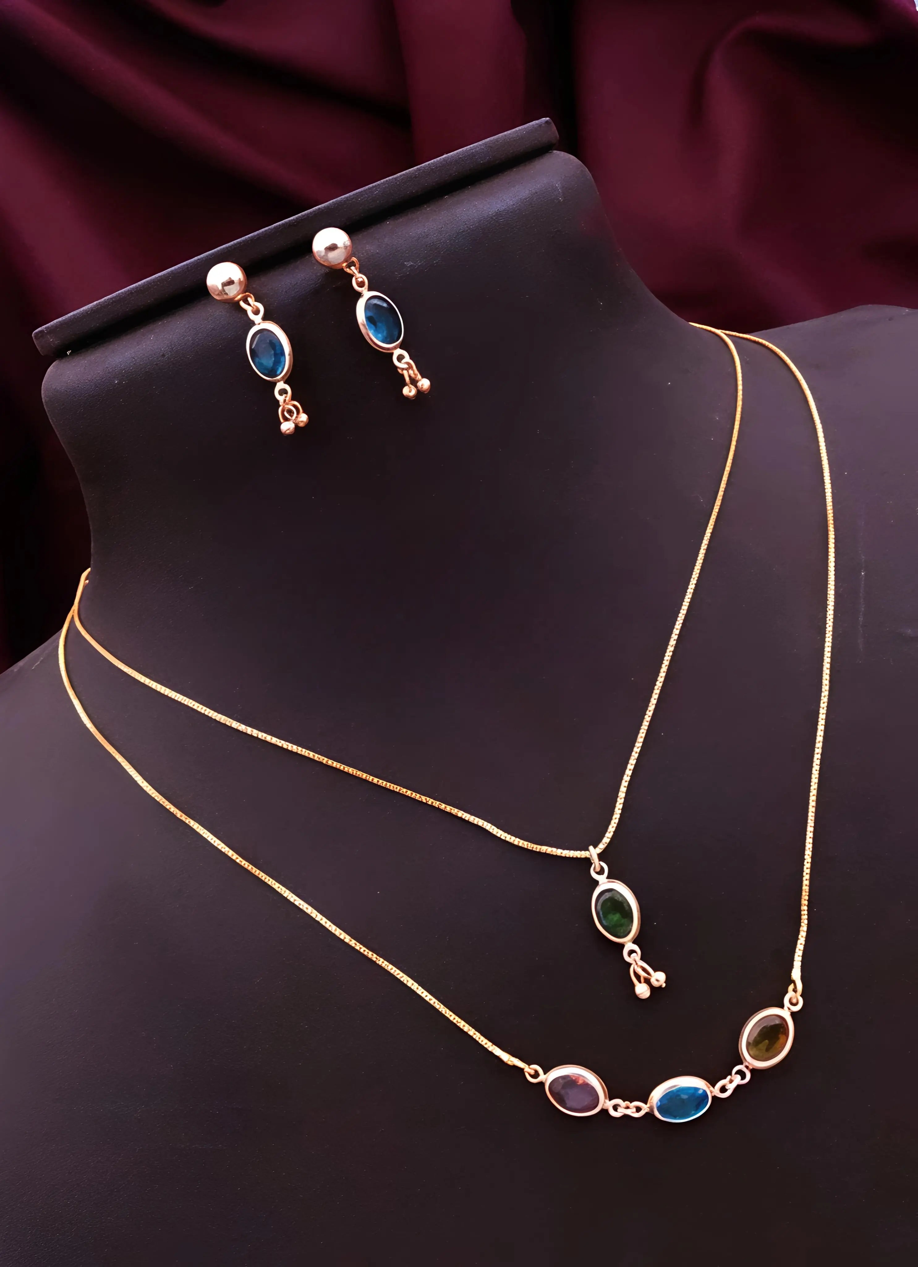 Gold necklace and earrings with gemstones on a black mannequin bust.
