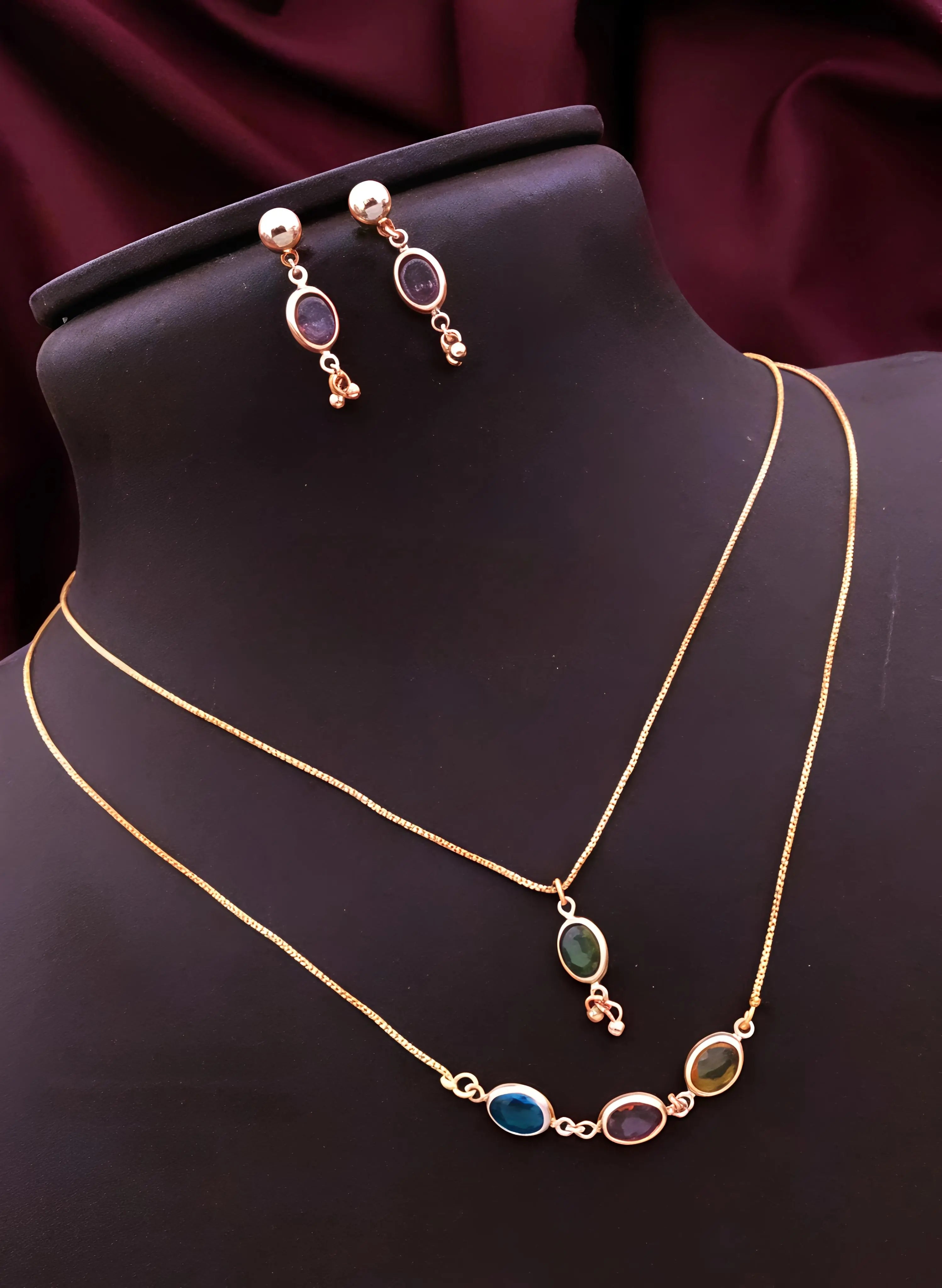 Gold necklace with gemstones and matching earrings on a mannequin against a dark background